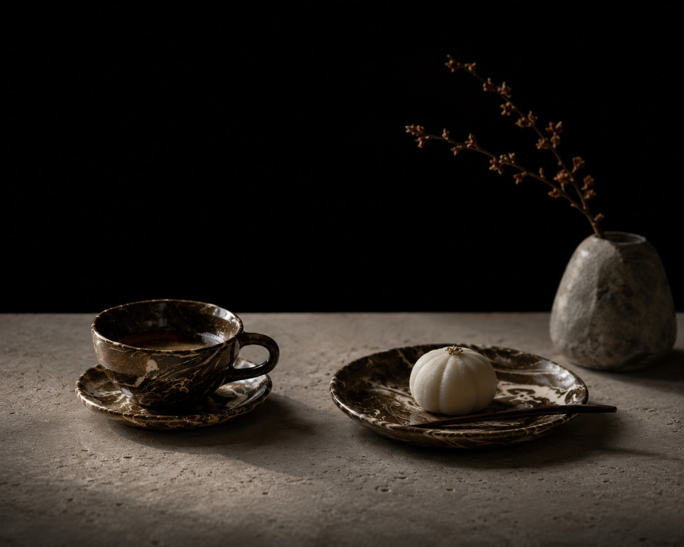 Ceramic cup and saucer with a small white pumpkin on a dark surface